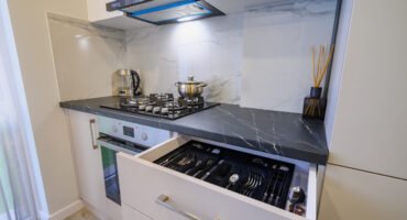Luxury beige and cream kitchen interior details, some drawers retracted, high angle view